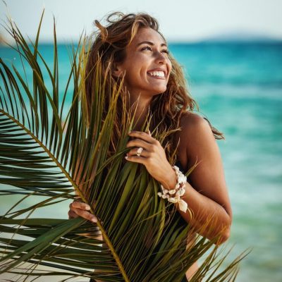 portrait-attractive-young-woman-is-posing-enjoying-covered-with-palm-tree-leaf-tropical-beach_360066-21097
